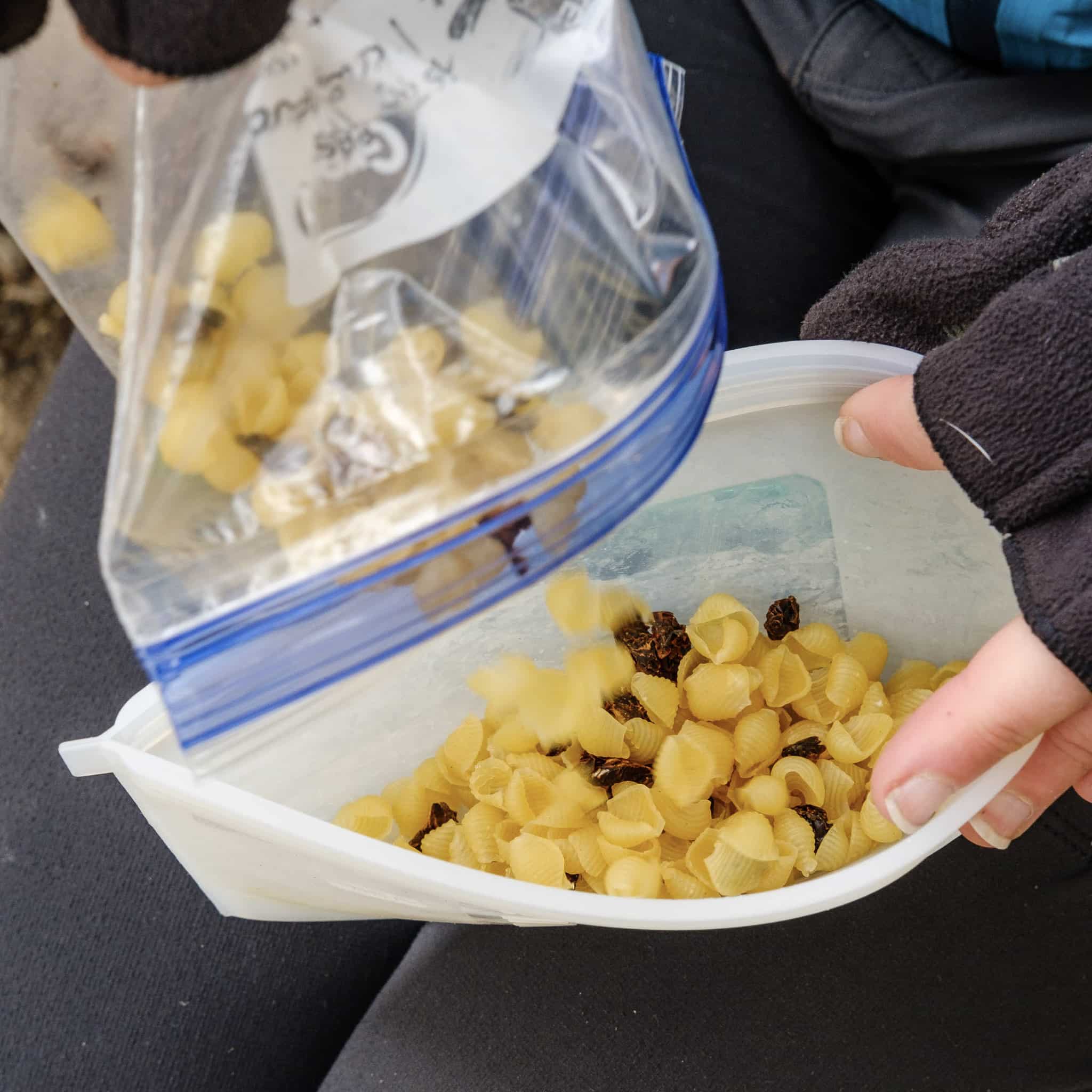 dumping sun dried tomato pesto pasta salad ingredients into silicone bag