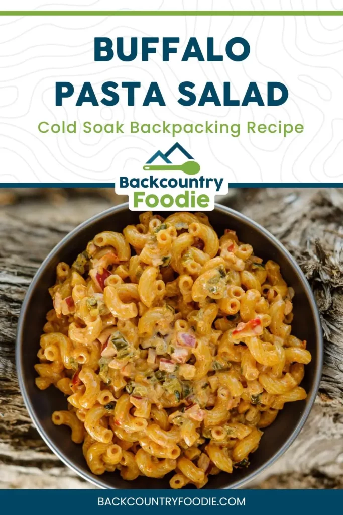 Bowl of creamy buffalo pasta salad with red peppers and green veggies, labeled as an ultralight cold soak backpacking recipe by Backcountry Foodie.