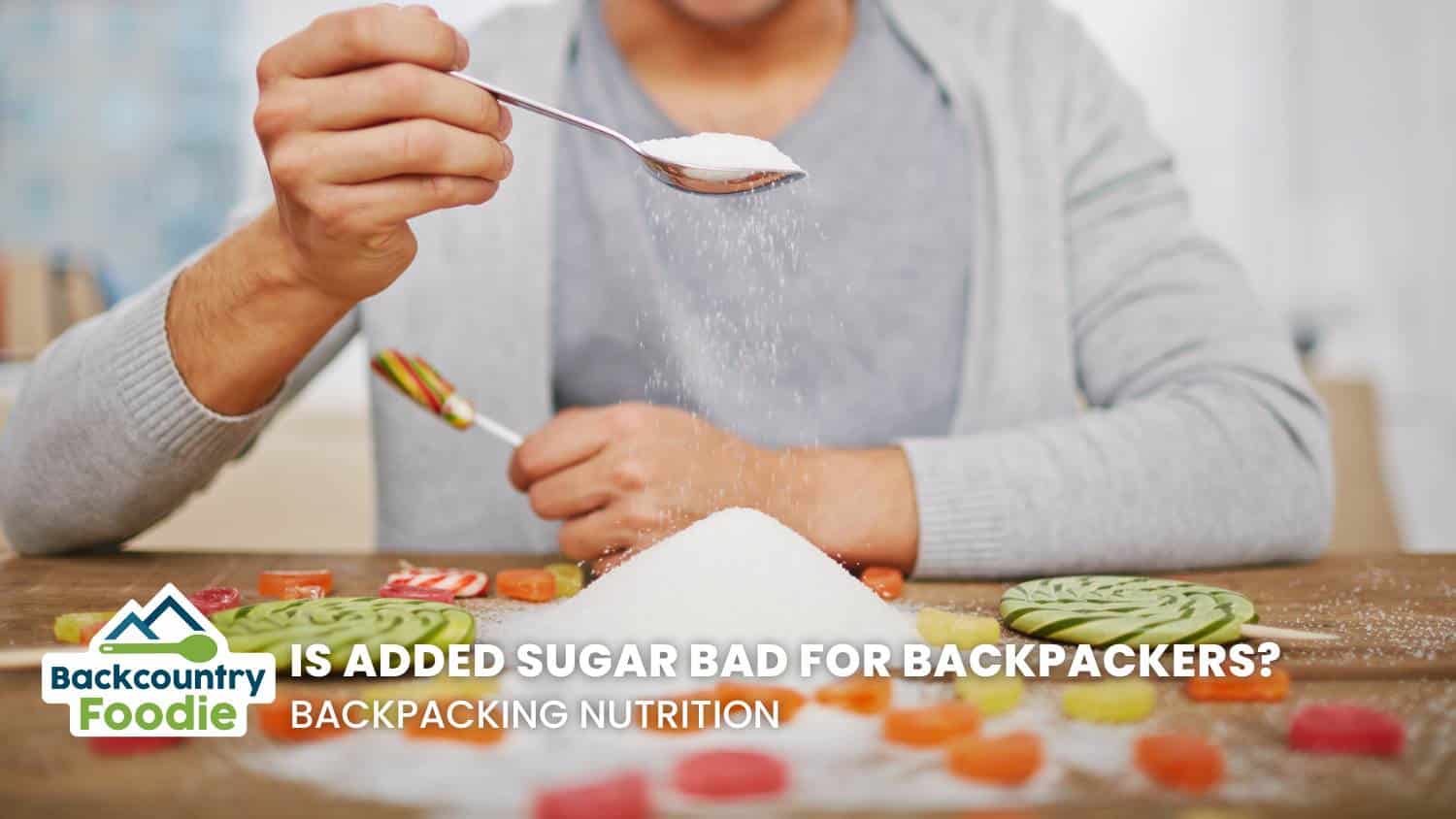 Is Added Sugar Bad For Backpackers Backcountry Foodie Blog person holding teaspoon of sugar with candy on the table