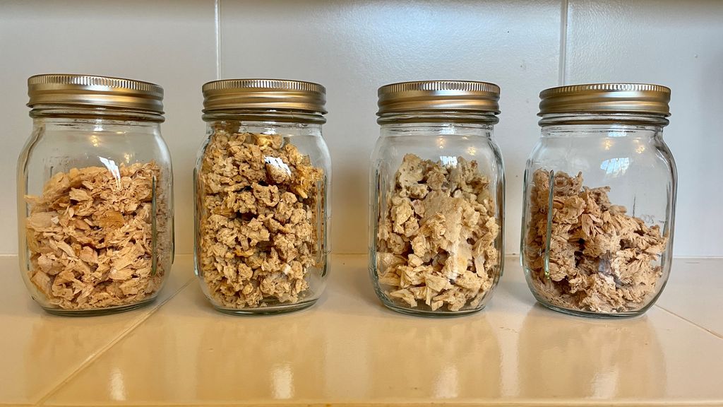 Four glass mason jars filled with dehydrated and freeze dried tuna for long-term storage to be used for backpacking meals.