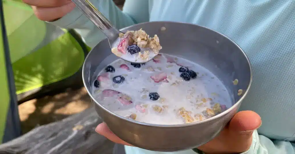 granola milk berries hiker holding spoon bowl social media image