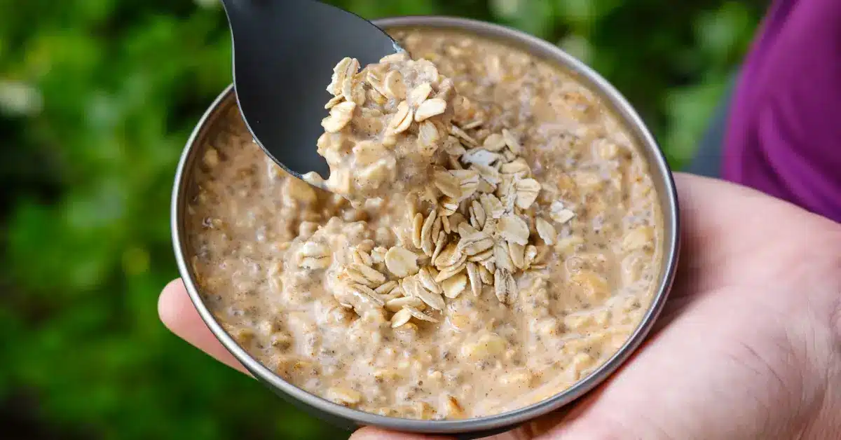 Nut butter cold-soak oats served in a backpacking bowl with a spoonful of creamy, high-calorie oatmeal – an ultralight no-cook breakfast for the trail.