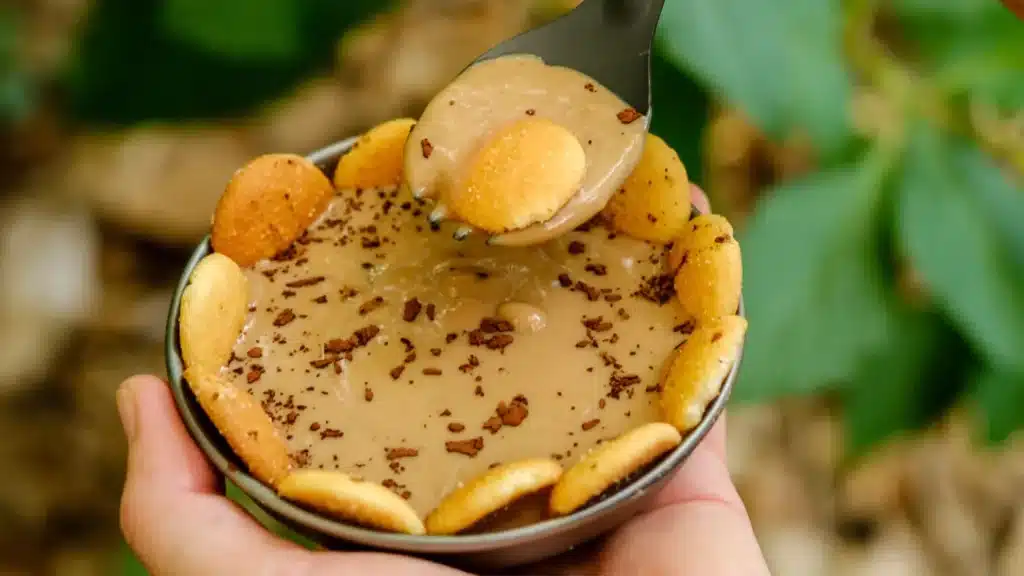 Cold soak hiking dessert topped with chocolate shavings and vanilla wafers, held outdoors in a trail setting